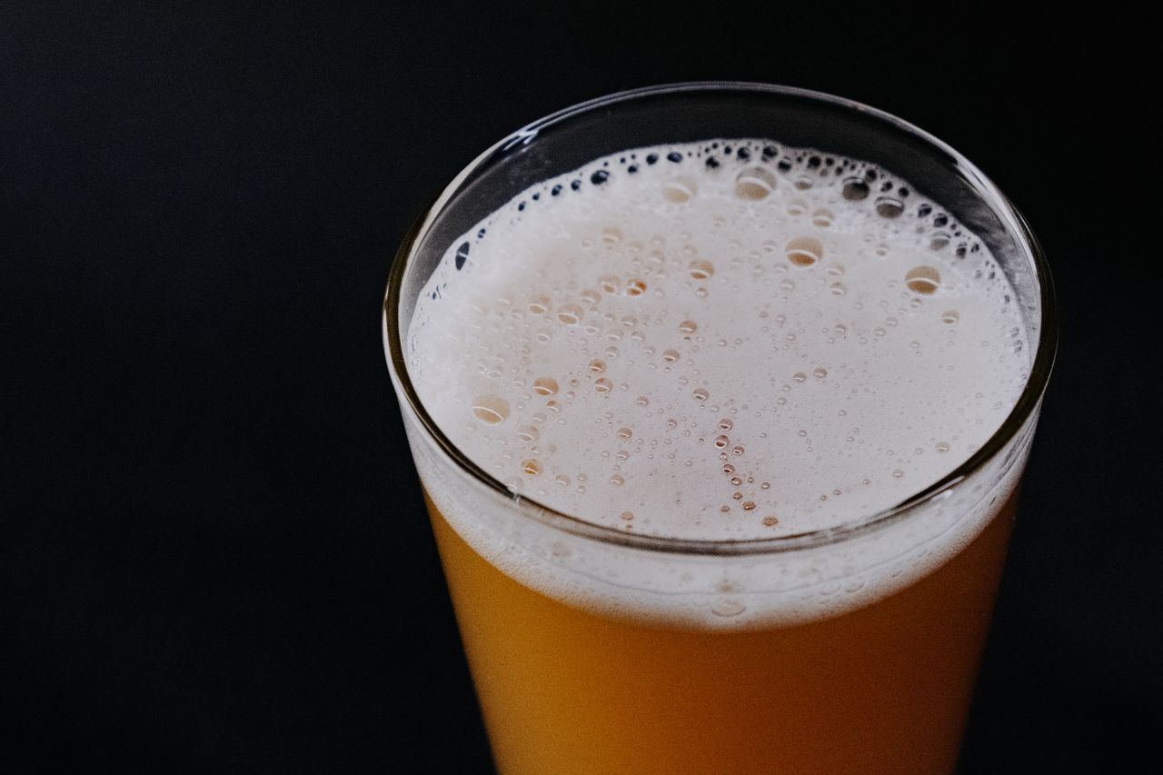 Close-up of a frothy beer in a glass over a dark backdrop, perfect for Oktoberfest-related themes.